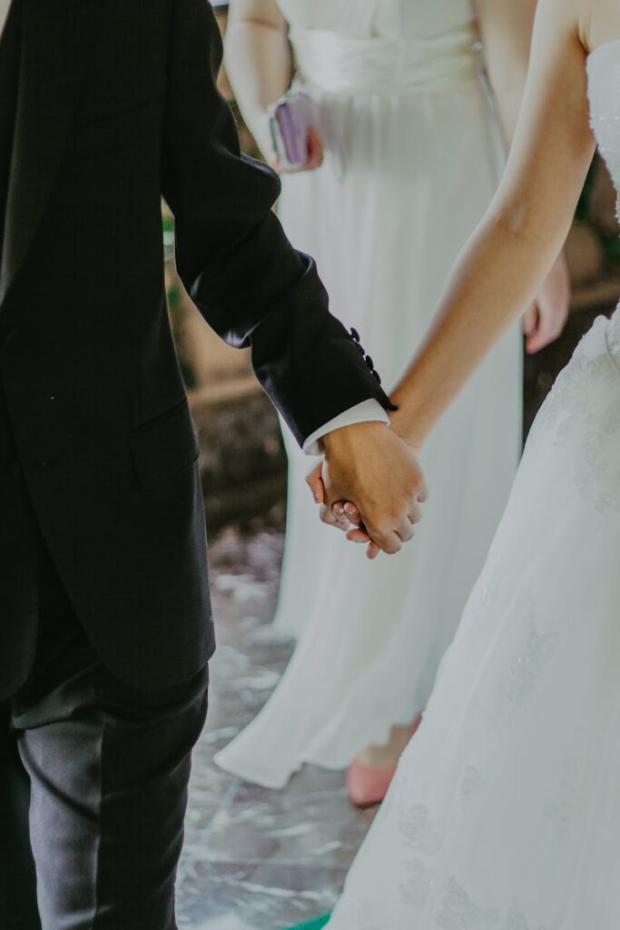 Woman Wearing White Wedding Gown Holding Hands With Man While Walking