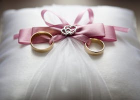 Selective Focus Photography of Silver-colored Engagement Ring Set With Pink Bow Accent on Throw Pillow