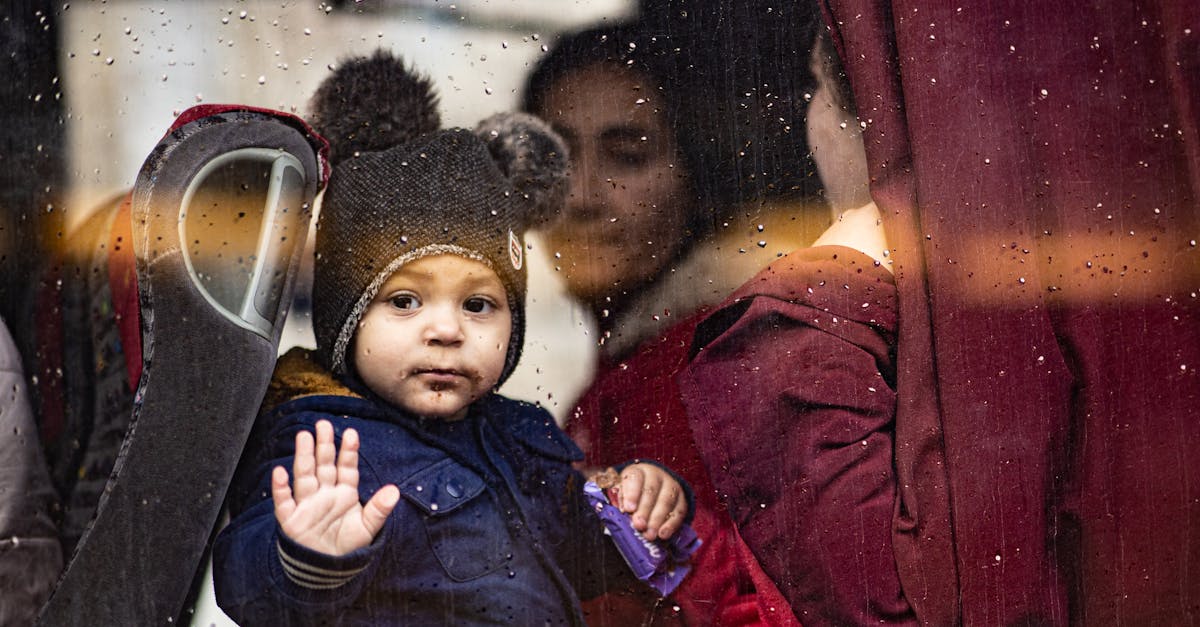 A young child waves from inside a bus on a rainy day in Budapest, Hungary, showcasing a moment of exploration and travel.