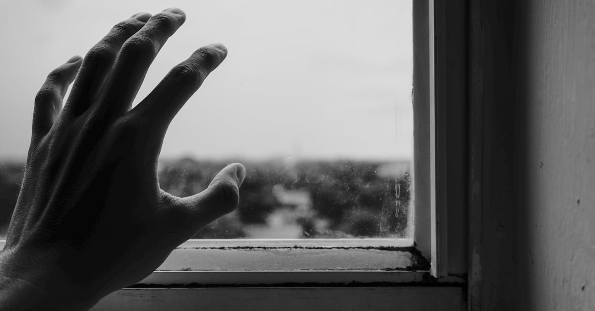 Abstract monochrome photo of a hand reaching towards a window, symbolizing longing.