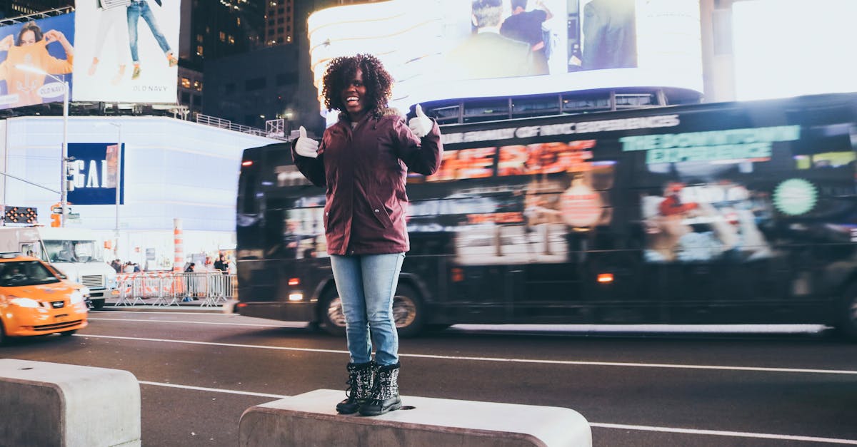 A smiling woman poses in Times Square with vibrant neon lights and bustling city life.