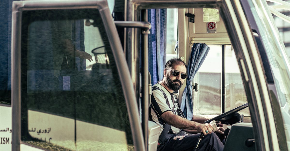 Confident bus driver in sunglasses sits behind the wheel, ready for travel.