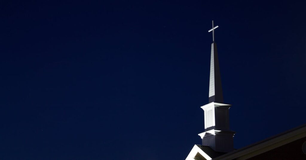 Illuminated church steeple with cross at night. Perfect for religious and architectural themes.