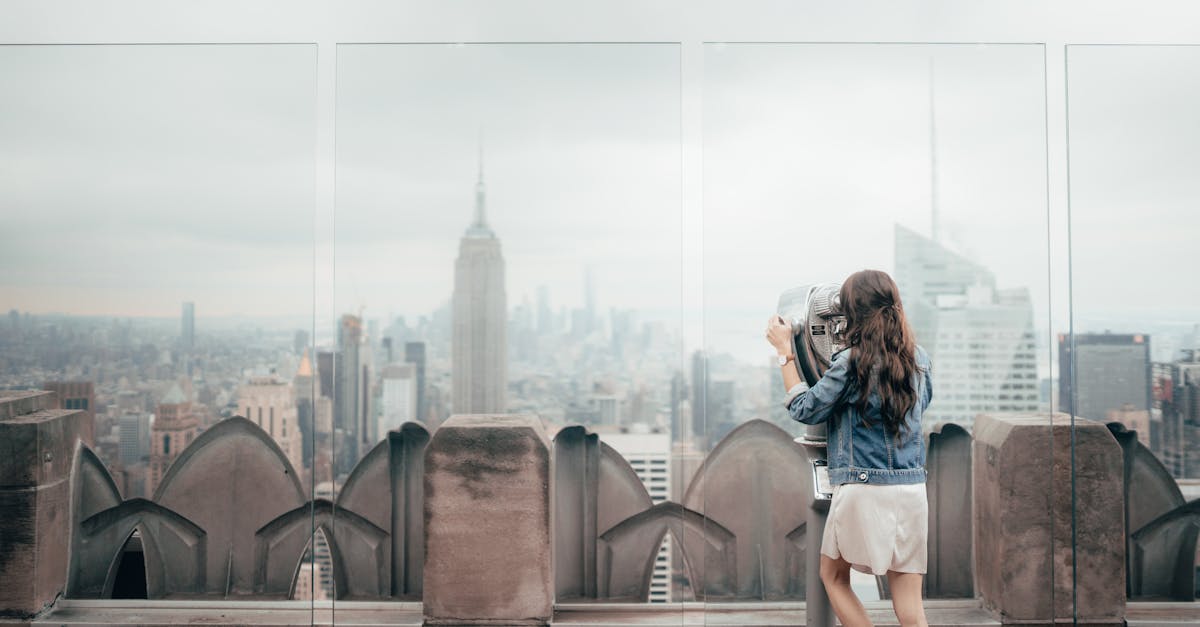 Woman viewing New York City skyline from Rockefeller Center with binoculars.