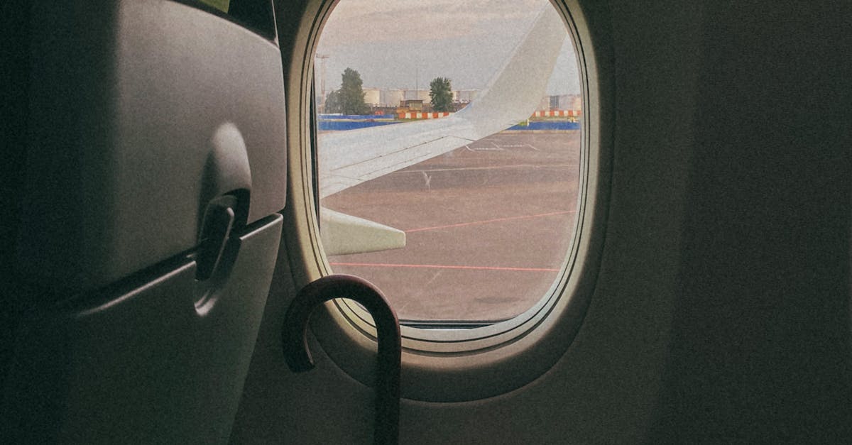 Looking out from an airplane window revealing an aircraft wing and yellow umbrella inside, ambient light.