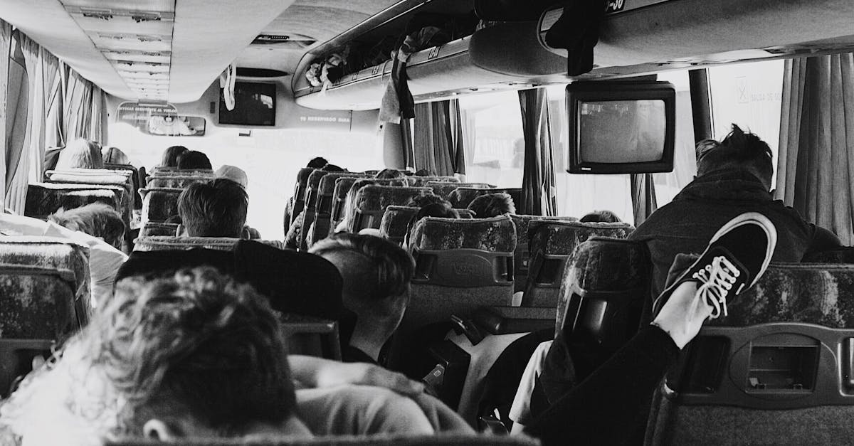 A monochrome view inside a bus full of seated passengers on a journey.