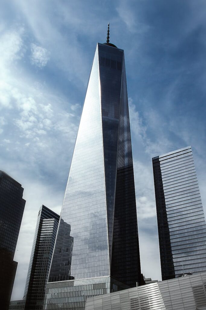 A striking view of One World Trade Center surrounded by skyscrapers against a clear blue sky.